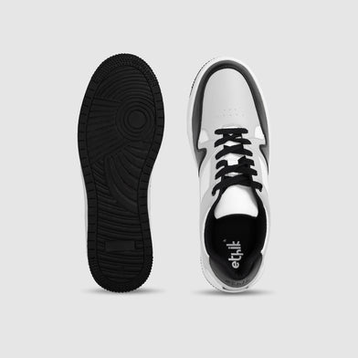 White sneakers with black laces and sole on a light gray background