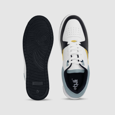 White sneaker with black sole and yellow accents on a light gray background