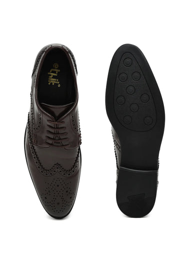Black leather dress shoes with brogue detailing on a white background