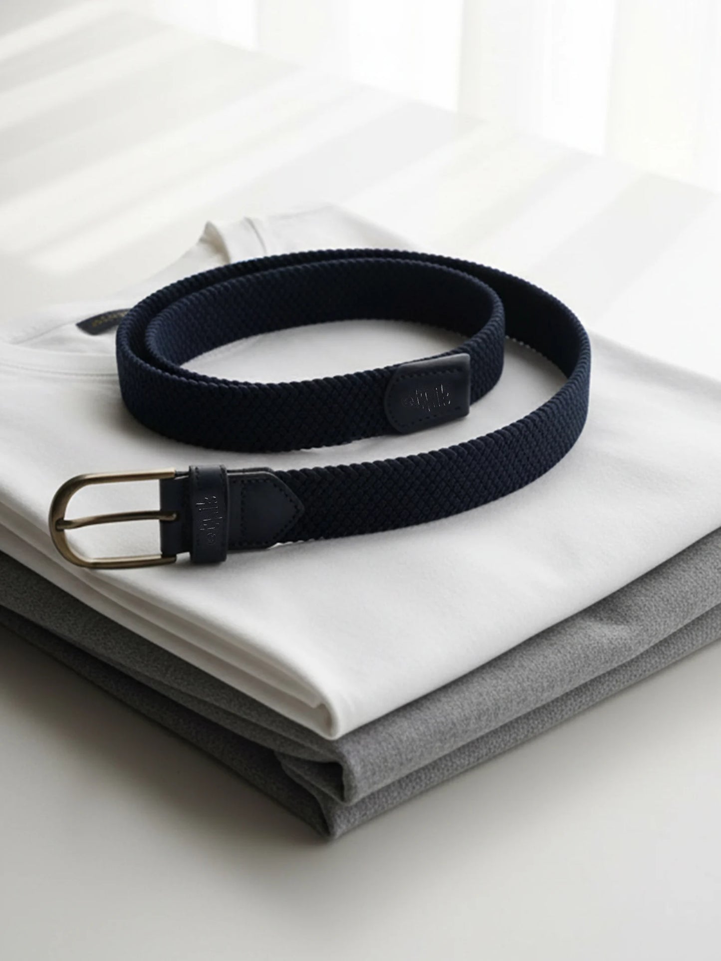 Navy belt with a gold buckle on a white shirt and gray pants