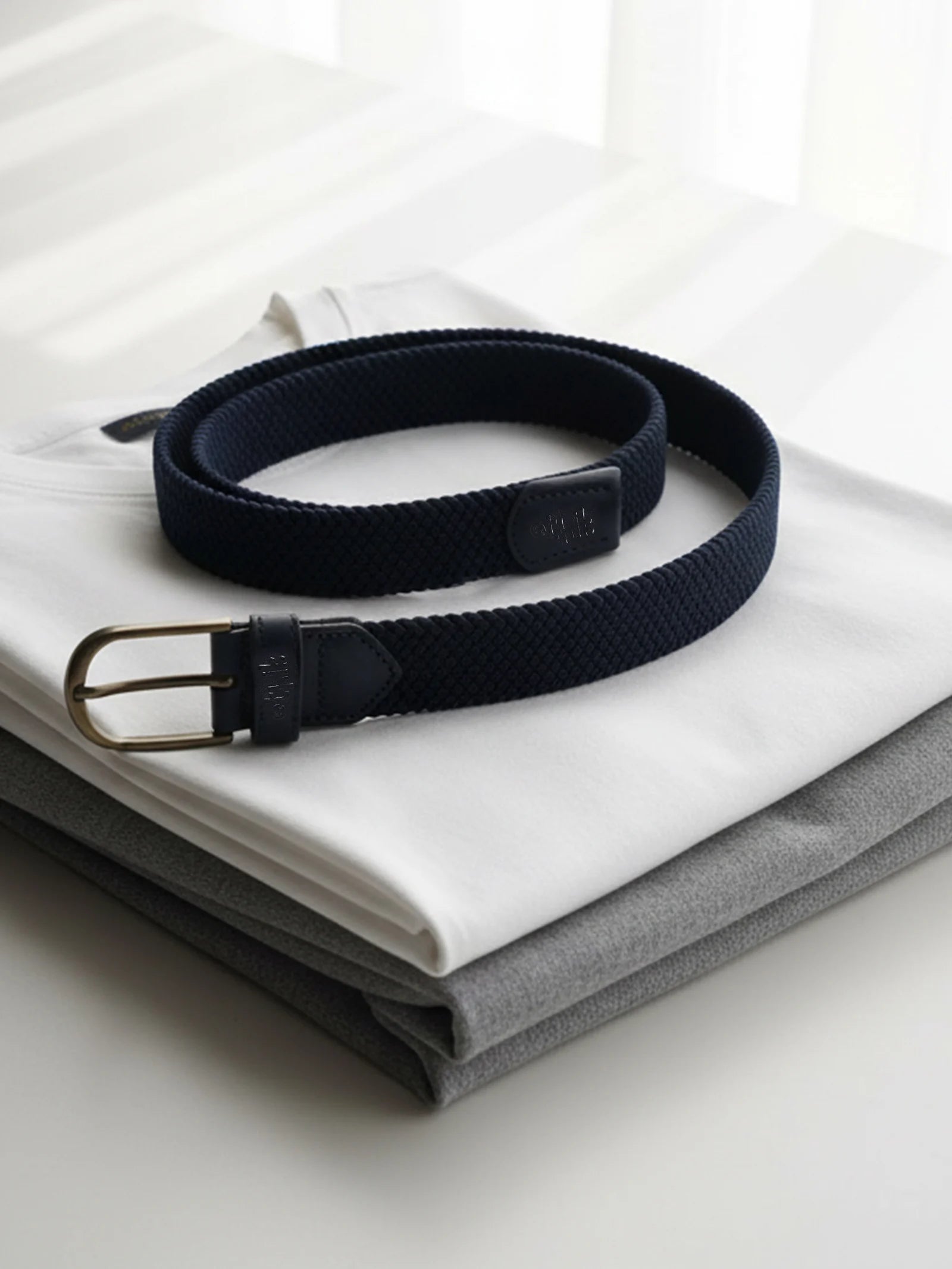 Navy belt with a gold buckle on a white shirt and gray pants