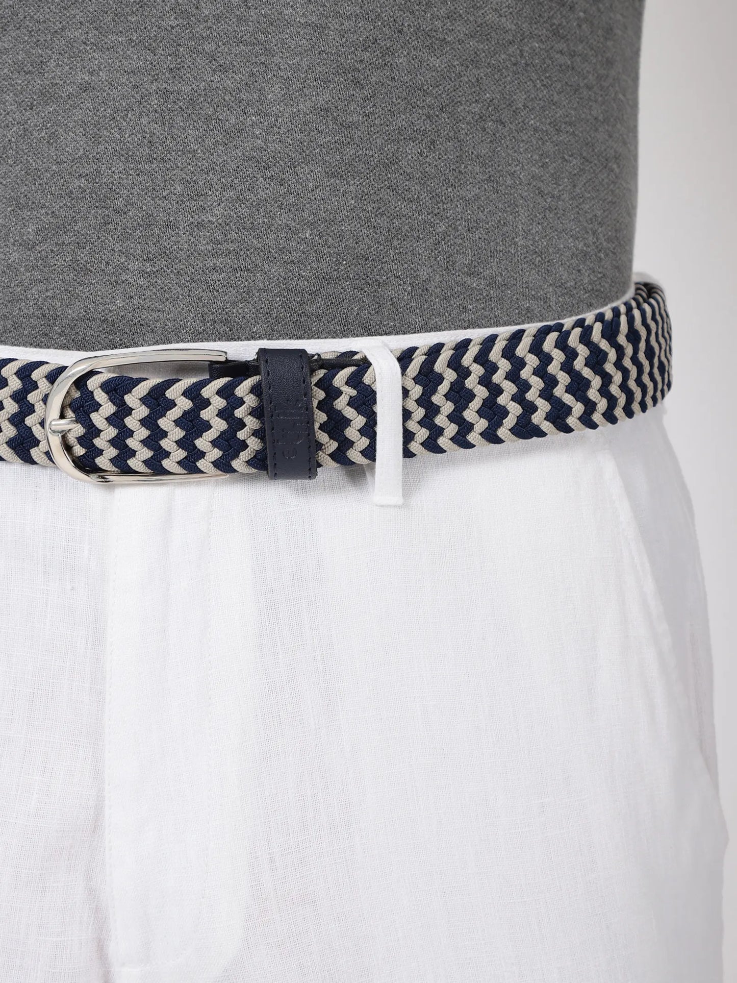 Navy and beige striped belt worn by a person with a gray shirt and white pants.