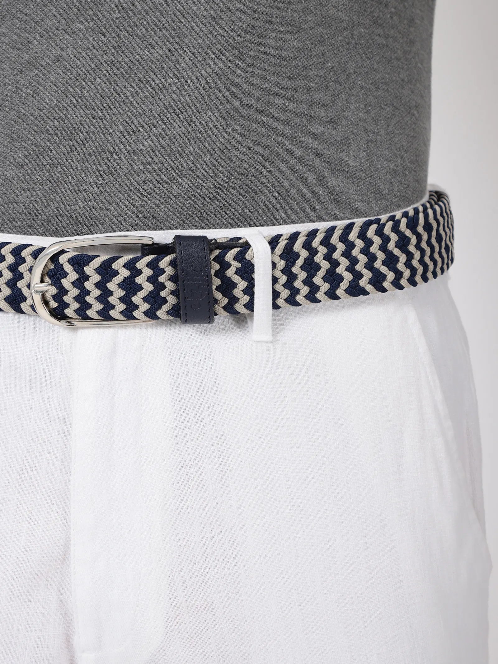 Navy and beige striped belt worn by a person with a gray shirt and white pants.